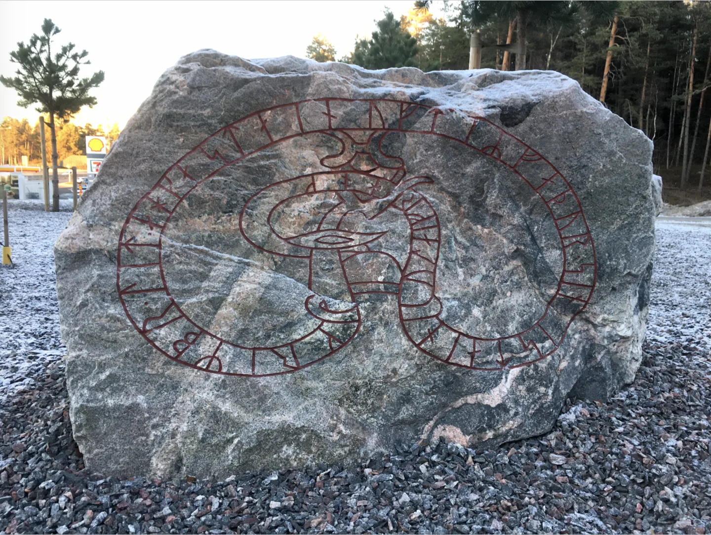 Grov grå sten med röd runorm som slingrar sig i en stor åtta över ytan.